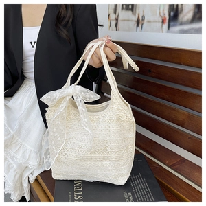 Detail of white lace tote bag featuring an elegant side bow and intricate crochet texture