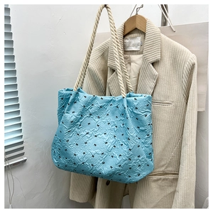 Macro detail of light blue quilted tote with black bows and thick rope handles