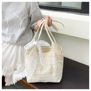 Detail of white crochet lace tote bag featuring intricate floral mesh and decorative bow
