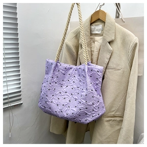 Detail of lavender tote bag with pleats, black bows and rope handles on a blazer