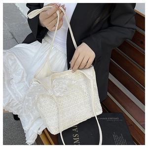 Close-up of white lace tote bag featuring intricate floral embroidery and a ribbon bow