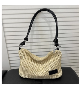 Detailed view of woven straw texture and black leather brand tag on a summer handbag