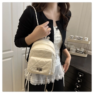 Detail of beige quilted backpack with silver clasp and leather-woven chain strap