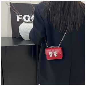 Rear view of a model wearing the red mini crossbody bag with silver bow and chain strap