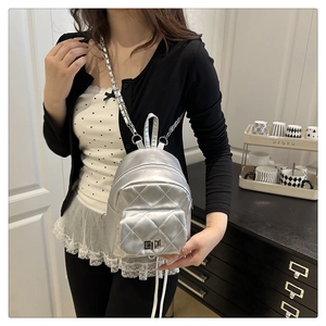 Detail of silver quilted mini backpack with metallic finish and metal chain strap