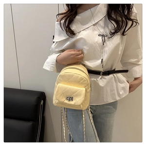 Detail of light yellow quilted mini backpack with metal chain strap and twist lock