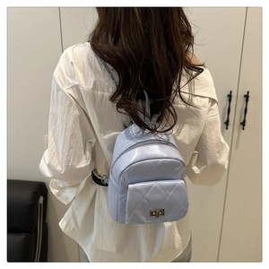 Detail of light blue quilted mini backpack with chain straps on model's back