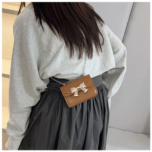 Close-up of caramel mini crossbody bag with silver metal bow and delicate chain strap