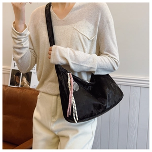 Detail view of black velvet crescent bag with pink rope knot and tennis racket charm