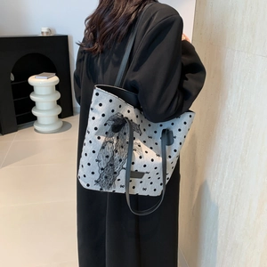 Sac fourre-tout en toile à pois avec grand nœud en dentelle noire porté par un mannequin