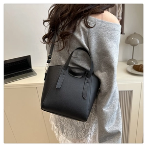 Mannequin portant un sac seau noir en cuir grainé avec des finitions dorées élégantes