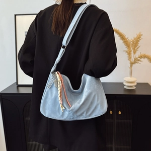 Light blue large hobo bag in suede texture with decorative rope charms and metal tag