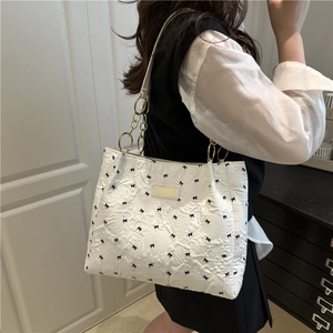 Borsa tote bianca plissettata con fiocchi neri e tracolla dorata indossata dalla modella