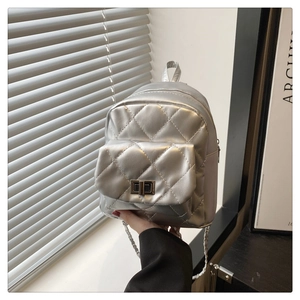 Close-up of silver quilted mini backpack featuring chain straps and metal twist lock detail