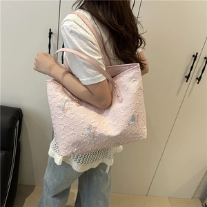 Pink tote bag with butterfly embroidery and embossed texture worn by a model