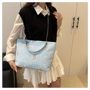Detail of light blue tote bag with butterfly embroidery and metal chain strap