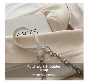 Close-up of the beige shoulder bag showing the white leather and silver metal chain strap