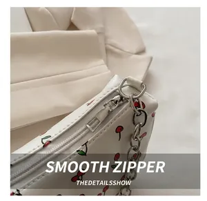 Detailed close-up of smooth silver zipper on a white bag with cherry prints