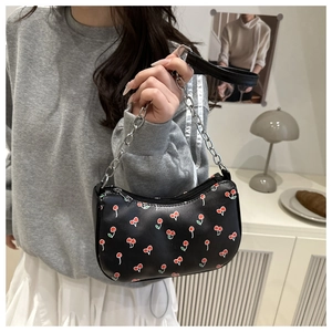 Détail du sac bandoulière demi-lune noir avec motifs cerises et chaîne argentée