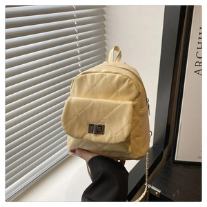 Close-up of a pale yellow quilted mini backpack with metallic twist-lock and chain straps