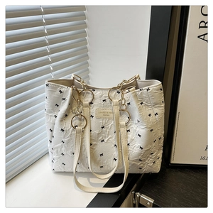 Détail du sac cabas blanc avec motifs de nœuds noirs et poignées en chaîne dorée