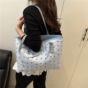 Stylish light blue pleated tote bag with black bow patterns and elegant shoulder straps