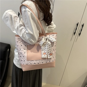 Pink quilted tote bag with silk scarf charm shown on a model in a minimalist setting