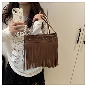 Détail d'un sac à main en cuir marron avec de longues franges et des rivets argentés