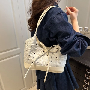 Elegant cream quilted shoulder bag with navy blue bow embroidery and ribbon side ties