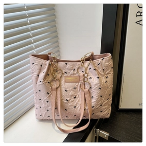 Détail d'un sac cabas rose à motifs de nœuds noirs et anse en chaîne dorée et cuir rose
