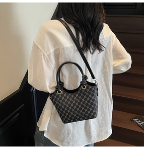 Détail d'un sac seau noir à motifs avec poignées nouées et ferrures dorées vintage