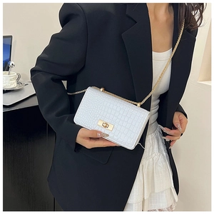 Detail of white crocodile pattern small square bag with gold chain strap on model