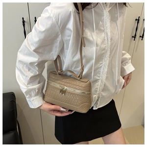 Detail of crocodile embossed texture on a beige vanity bag with gold dual zipper accents
