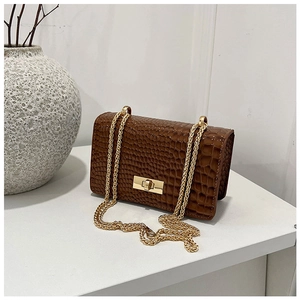 Detail of caramel crocodile pattern crossbody bag with gold chain and metal lock closure