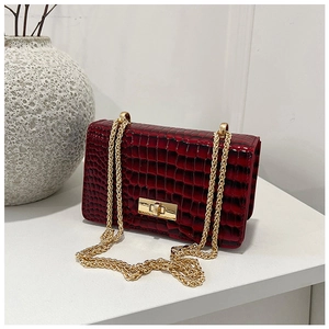 Detail of burgundy crocodile-embossed patent leather bag with gold chain and square lock