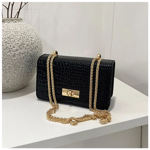 Close-up of glossy black crocodile-embossed leather texture and gold chain strap detail