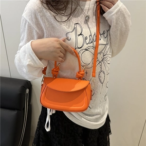 Bright orange leather mini crossbody bag with unique braided handle and gold metal hardware