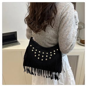 Detail of a vintage black fringed bag with gold studs on textured matte suede