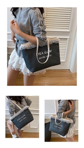 Detail view of large black denim tote bag featuring white double lace trim and EVEA GLOW logo
