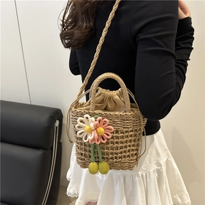 Summer handmade straw bucket bag with floral charm and woven strap shown on model