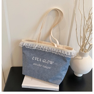 Detail of light blue denim tote bag featuring white lace edges and minimalist typography