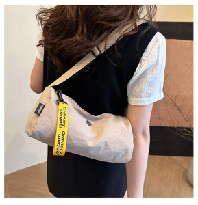 Vue détaillée du sac bandoulière en nylon beige avec ruban décoratif jaune vif