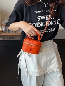 Orange quilted square mini crossbody bag with gold chain strap shown on model