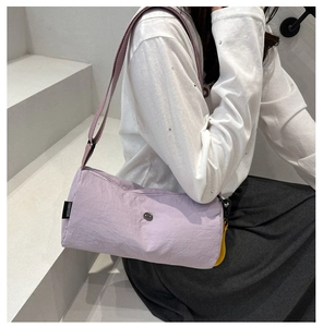 Détail du sac cylindrique violet clair montrant la texture en nylon et l'étiquette logo