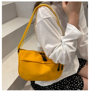 Close-up of bright yellow half-moon canvas shoulder bag with a stylish zipper puller