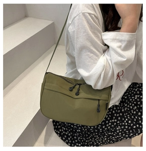 Close-up of military green nylon crossbody bag with dual-zipper detail on model