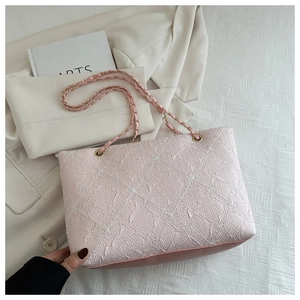 Detail of pink textured tote bag with chain strap and luxury embroidered fabric finish