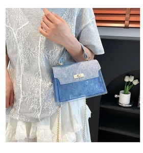 Dettaglio della borsa in PVC blu trasparente con patta glitterata e chiusura a girello oro