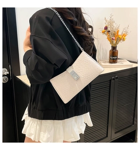 Détail du sac bandoulière crème avec texture crocodile et bandoulière chaîne