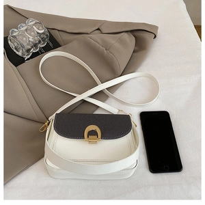 Détail du sac bandoulière bicolore avec boucle dorée en fer à cheval et taille smartphone